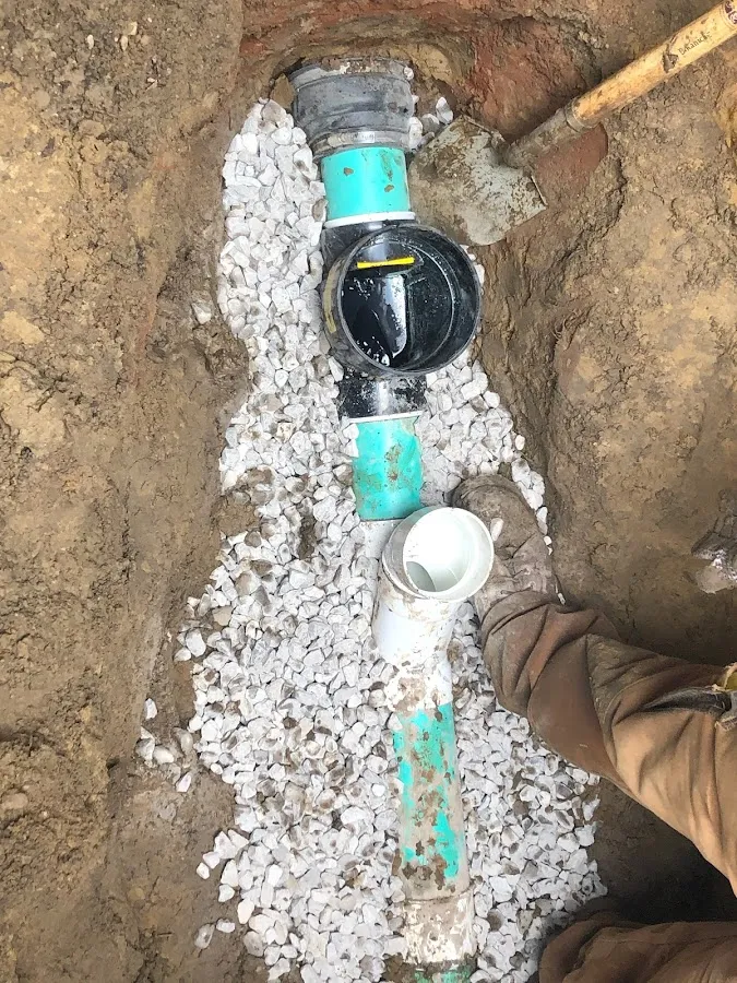 Blue PVC drain line laid in foundation trench with gray stone aggregate support base