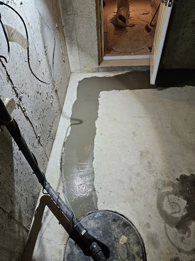 Basement floor showing water damage and restoration work with dehumidifier equipment